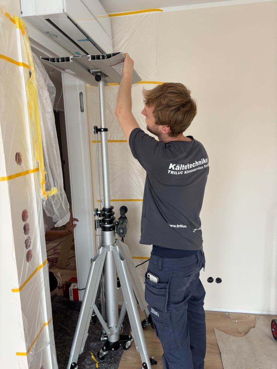 Ein TRILUC Kältetechniker hebt mit einem spezial Lift ein hochwertiges Mitsubishi Diamond Klimagerät an den installationsort über der Tür.