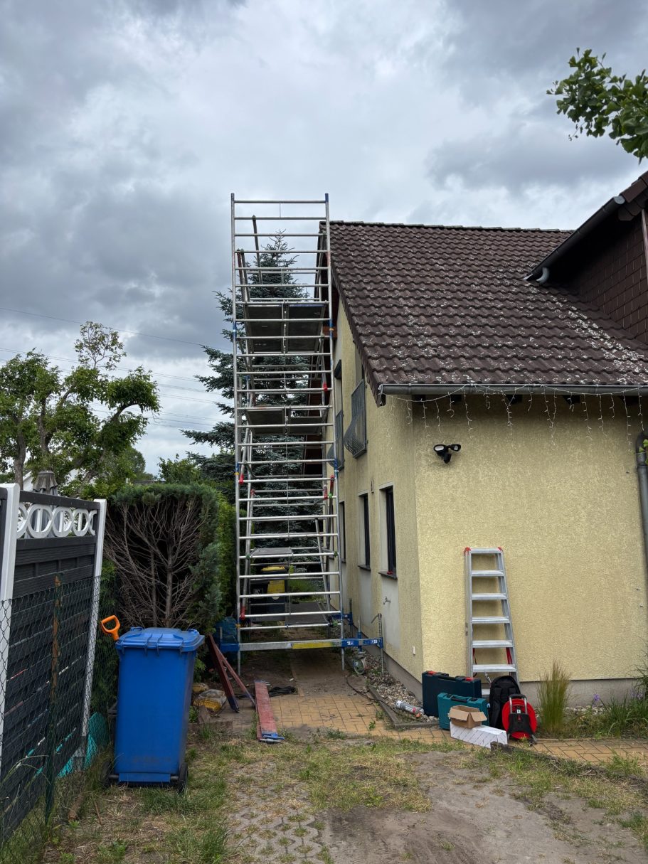 Gerüst von TRILUC neben einem Einfamilienhausaus, mit Werkzeugen im Vordergrund. Vorbereitungsmaßnahme für die Klimaanlageninstallation. 